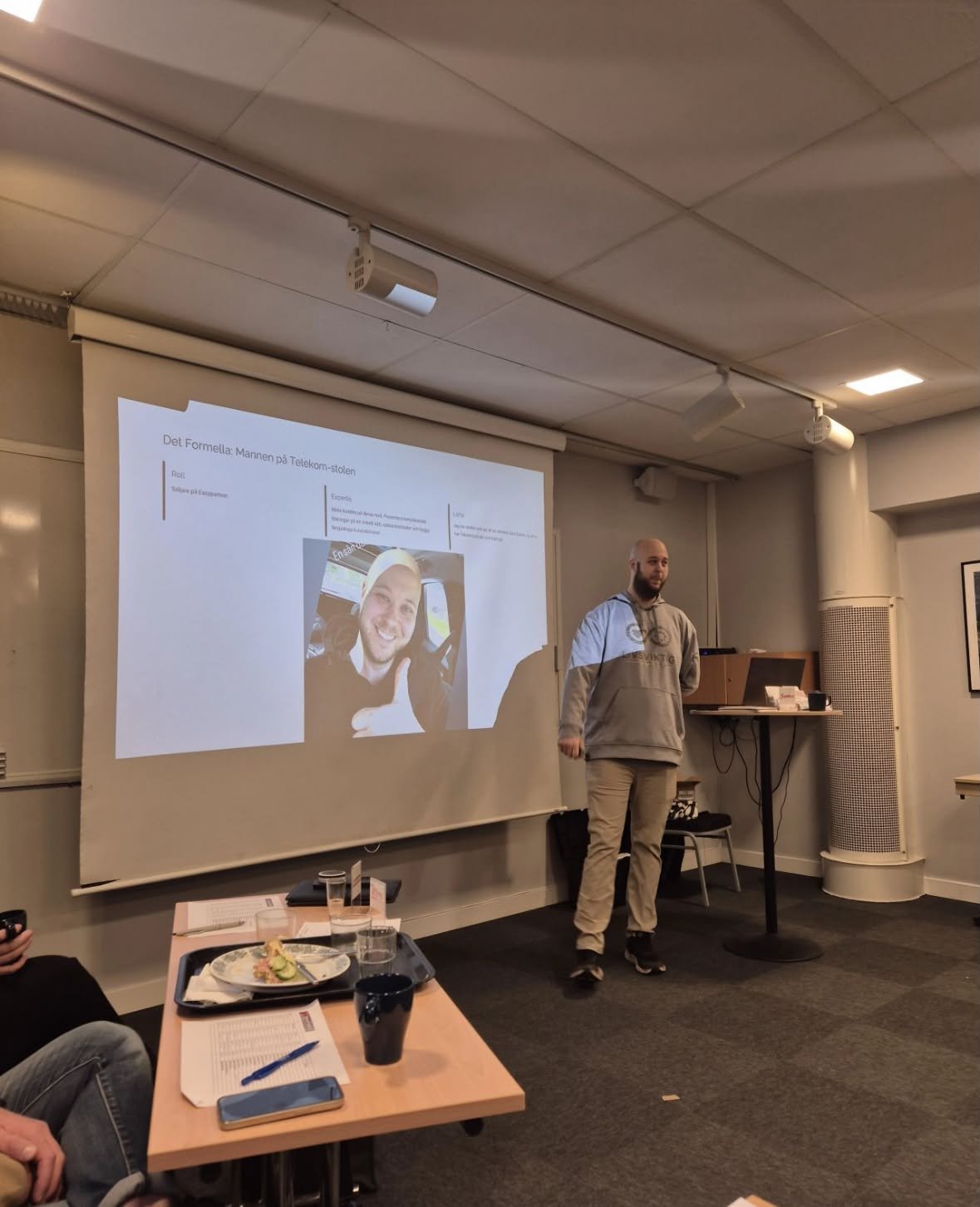 Tobiaz håller en presentation framför en projektorduk